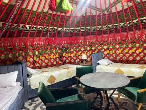 une chambre avec deux lits, une table et des chaises dans l'établissement Turan Handmade Yurt with Heated Floors, à Karakol
