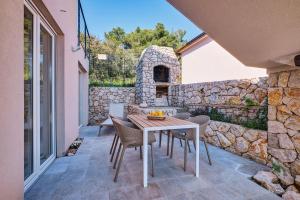 a patio with a table and chairs and a stone wall at VILLA RITA ARTaTORE in Mali Lošinj