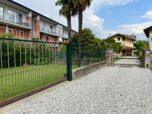 a fence in front of a building with a palm tree at CASA MIMOSA check-in on line in Domaso