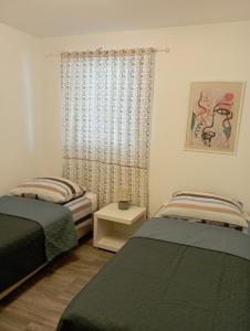 a bedroom with two beds and a window at Apartments Frigan in Maslenica
