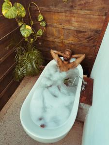 un hombre sentado en una bañera en un baño en La Maracuya Panama, en Playa Coronado