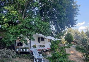 une caravane blanche garée dans une cour à côté d'un arbre dans l'établissement Paradise Agricamp, à Roccastrada