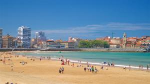 un grupo de personas en una playa cerca del océano en Playa - Garaje - Moderno - Arena23, en Gijón