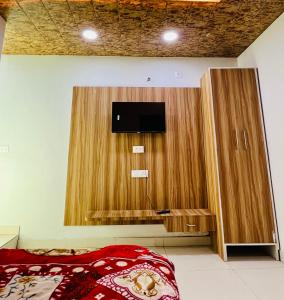 a bedroom with a tv in a wooden cabinet at Shri Hari Cottage in Mathura