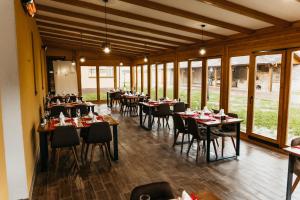 a dining room with tables and chairs and windows at Pansion Mihića dvori in Babina Greda