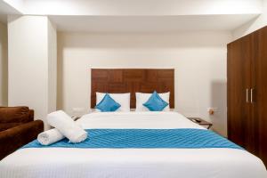 a bedroom with a large white bed with blue pillows at Monday Hotels Swarna's The Capital in Vijayawāda