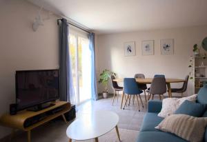 ein Wohnzimmer mit einem blauen Sofa und einem Tisch in der Unterkunft Maison calme avec jardin proche de Toulouse in Odars