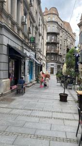 una calle de la ciudad con edificios y personas sentadas en bancos en Talia Apartments, en Belgrado