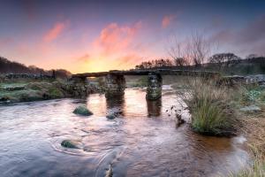 an old stone bridge over a river at sunset at The Luxury Dartmoor Den, Dartmoor, Devon in Ashburton