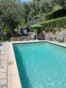 uma piscina com um guarda-sol, uma mesa e cadeiras em Villa Daphné em Spéracèdes