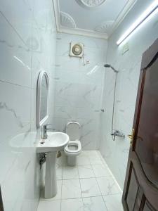 a white bathroom with a toilet and a sink at نسائم العنبرية in Al Madinah