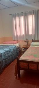 Un dormitorio con dos camas y una ventana con cortinas. en Casa cálida el hornocal, en Humahuaca