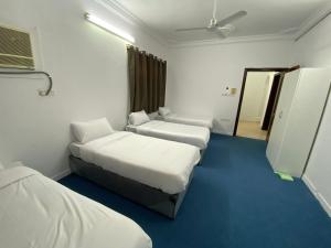Habitación de hotel con 3 camas y espejo en نسائم العنبرية en Medina