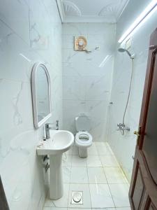 a white bathroom with a toilet and a sink at نسائم العنبرية in Al Madinah