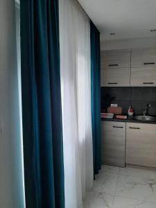 a room with blue and white curtains and a kitchen at Nikolic Apartment 2 in Leskovac