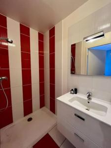 - une salle de bains rouge et blanche avec lavabo et miroir dans l'établissement Jolie maison de Ville au Mans, au Mans