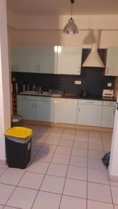 uma cozinha com armários brancos e um caixote do lixo amarelo em La petite pétillante em Reims