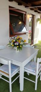 a white table with a vase of flowers on it at La Maisonette in SantʼAndrea