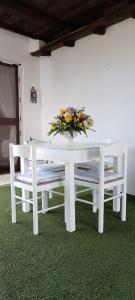 a white table and bench with a vase of flowers on it at La Maisonette in SantʼAndrea