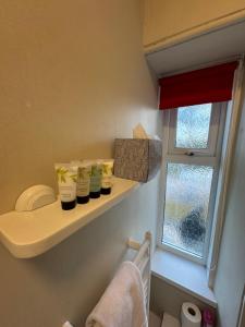 a bathroom with three bottles on a shelf next to a window at St Olaf Golf Hotel in Cruden Bay