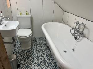 a bathroom with a tub and a toilet and a sink at The End House at The Old Farmhouse in Cowbridge +10 photos