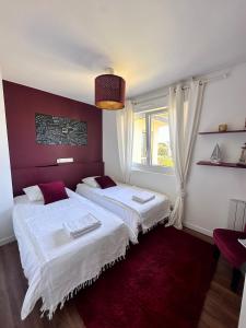 two beds in a bedroom with a red wall at Le LUXE & votre VUE MER à Ouistreham Riva Bella in Ouistreham