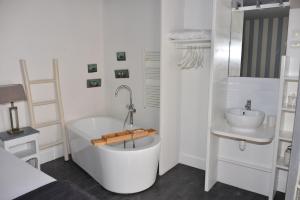 a white bathroom with a tub and a sink at La Villa du Grand Large in Biscarrosse