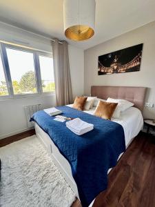 um quarto com uma cama grande e um cobertor azul em Le LUXE & votre VUE MER à Ouistreham Riva Bella em Ouistreham