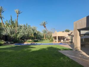 a large yard with palm trees and a building at Villa Sahar Palmeraie avec piscine chauffée ! in Marrakech
