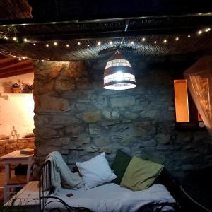 a room with a stone wall with a couch and a light at L'Essiccatoio in Fivizzano