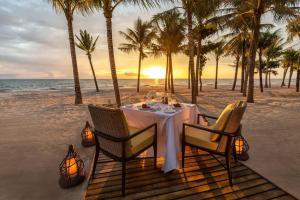 a dinner table on the beach with palm trees at Rosemary's in Ha Long