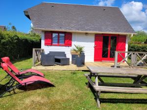 ein rotes und weißes Haus mit einem Tisch und einem Picknicktisch in der Unterkunft Chalet 31 in Saint-André-dʼHébertot