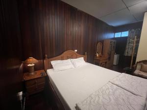 a bedroom with a white bed and a wooden wall at Ban Heng in Phra Nakhon Si Ayutthaya