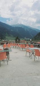a row of tables and chairs with mountains in the background at New Hilton Hotel in Naran