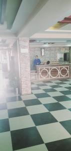 a man sitting on a bench in a room with a checkered floor at New Hilton Hotel in Naran