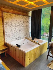 a large bath tub in a room with a large window at Lotus Çamlıhemşin Suit & Bungalov in Çamlıhemşin