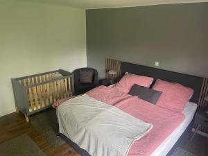 een slaapkamer met een bed met roze lakens en een wieg bij Ferienhaus Jahn in Barßel