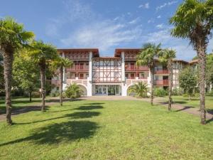 a large building with palm trees in front of it at Appartement Biscarrosse lac-golf in Biscarrosse