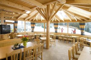 um restaurante com mesas e cadeiras de madeira e janelas em Familienhotel Moos-Alm em Lienz