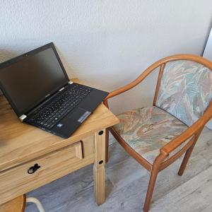 un ordenador portátil sentado en un escritorio de madera con una silla en Einzelzimmer am Hegensteinbach en Ravensbrück