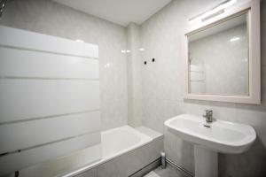 a white bathroom with a sink and a mirror at Dulces Estancias in Lalín