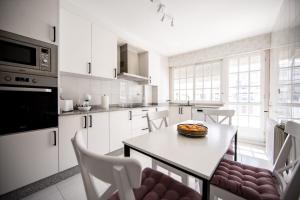 a kitchen with white cabinets and a table and chairs at Dulces Estancias in Lalín