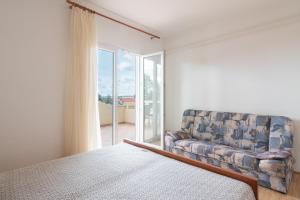 a bedroom with a bed and a couch and a window at Apartments Josipa in Mandre