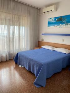 a bedroom with a blue bed and a window at Hotel Ariston in Sottomarina