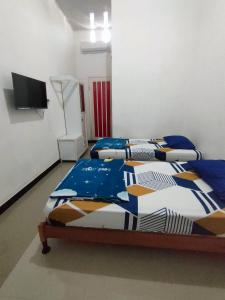 Cette chambre dispose de 2 lits et d'une télévision murale. dans l'établissement Hotel Residence 5 Syariah, à Bandung