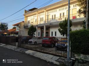 a fence in front of a building with parked cars at Hotel Residence 5 Syariah in Bandung