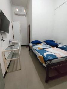 - une chambre avec un lit, un bureau et une télévision dans l'établissement Hotel Residence 5 Syariah, à Bandung