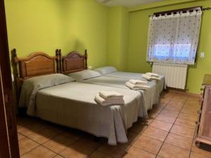 two beds in a green room with towels on them at Hotel El Cid in Torres de Albarracín