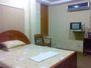 a room with a table and a television on a wall at Mughal Hotel in Sargodha