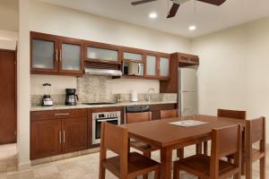 a kitchen with wooden cabinets and a wooden table with chairs at Acanto Hotel Playa del Carmen, Trademark Collection by Wyndham in Playa del Carmen